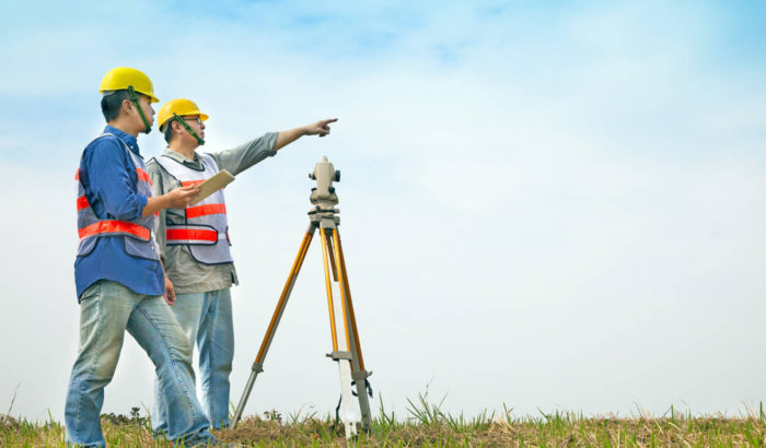 Surveyor engineer making measure with partner on the field